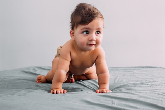 Lindo bebê engatinhando na cama no quarto, estilo de vida familiar