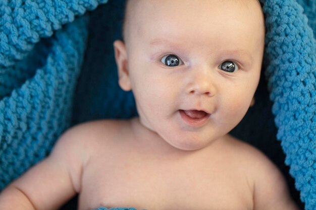 Un lindo bebé envuelto en una acogedora manta azul mirando a la cámara