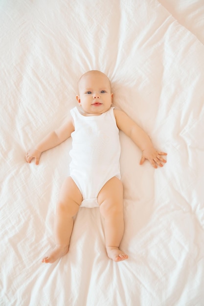 Lindo bebé está acostado en la cama en el dormitorio sonriendo