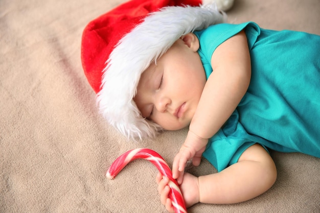 Lindo bebé con gorro de Papá Noel durmiendo sobre tela