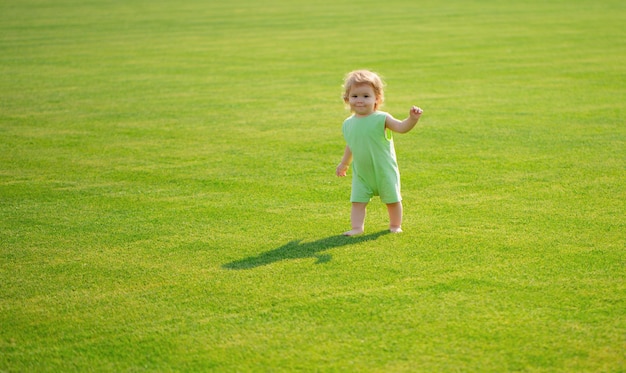 Foto lindo bebé gracioso aprendiendo a gatear paso divirtiéndose jugando en el césped en el jardín