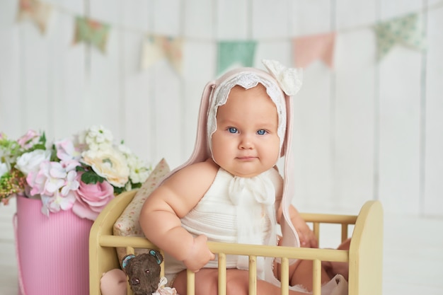 Lindo bebé gracioso con oreja de conejo. Linda niña de 6 meses en la cama