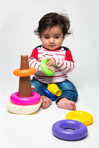 Lindo bebé indio o bebé o niño pequeño jugando con juguetes o bloques sobre fondo blanco.