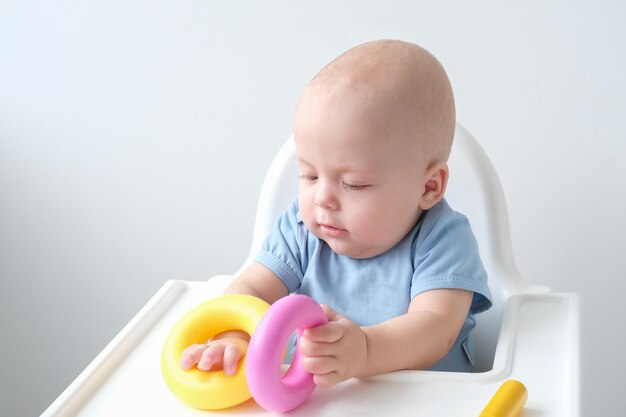 lindo bebé jugando con coloridos juguetes de plástico en la silla infantil desarrollo infantil temprano