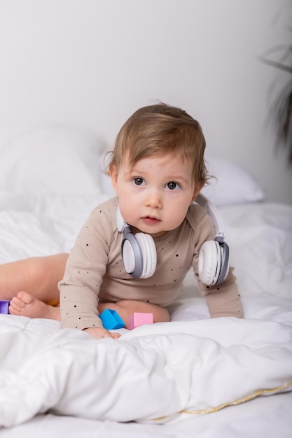 lindo bebé jugando con juguetes coloridos y auriculares en un espacio de banner de manta para texto