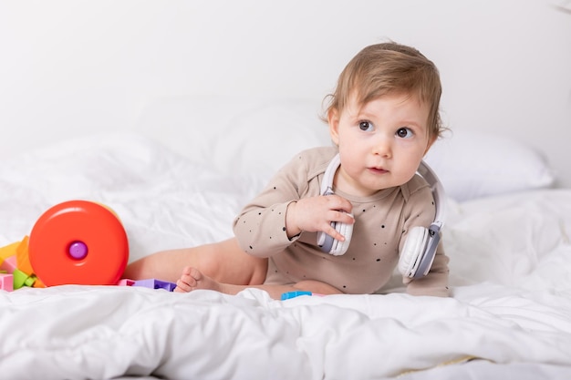 lindo bebé jugando con juguetes coloridos y auriculares en un espacio de banner de manta para texto