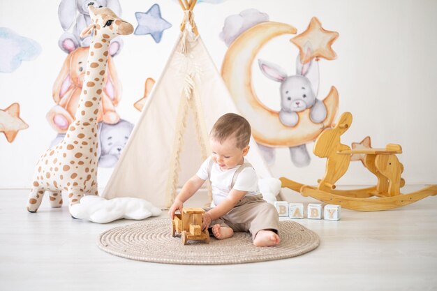 Lindo bebé jugando con juguetes naturales de madera en la habitación de los niños en casa juguetes educativos para niños