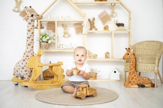 Lindo bebé jugando con juguetes naturales de madera en la habitación de los niños en casa juguetes educativos para niños