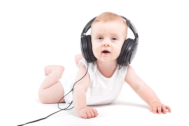 lindo bebé lindo en camisa blanca y auriculares en la cabeza