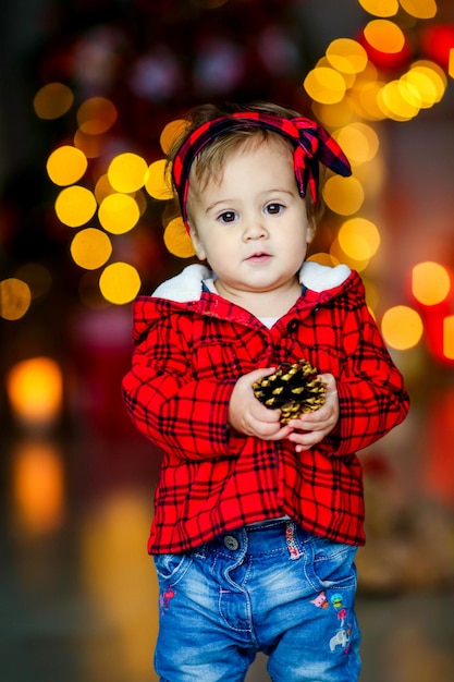 Foto lindo bebê na véspera de ano novo em meio a luzes festivas e brilhantes