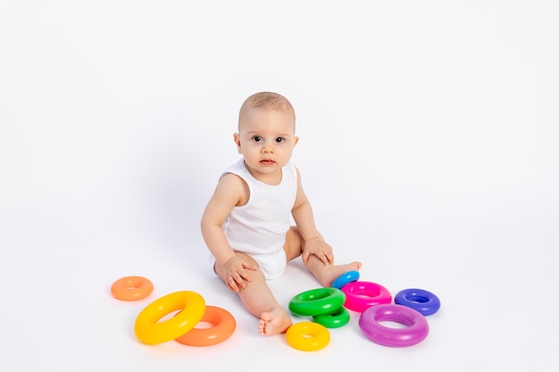 Lindo bebé niño de 8 meses jugando con una pirámide en blanco