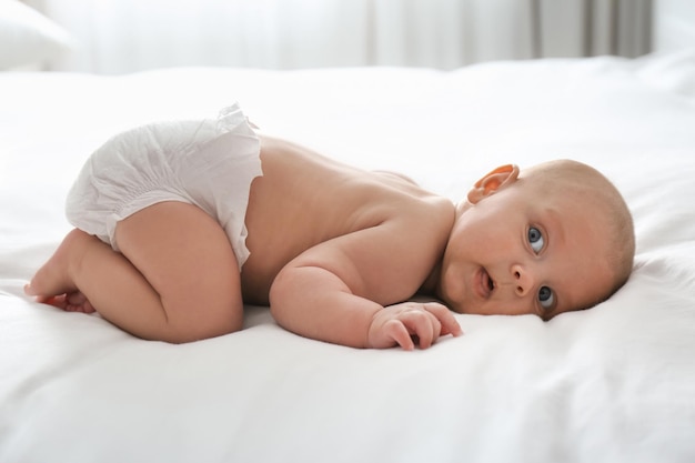 Lindo bebé en pañales en la cama en casa