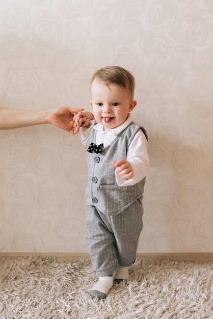 Lindo bebé de pie sosteniendo la mano de su madre, dando sus primeros pasos, una infancia feliz