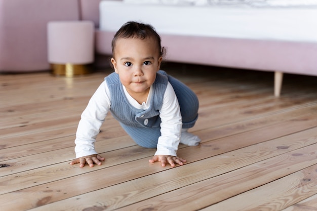 Foto lindo bebé posando y arrastrándose por el suelo