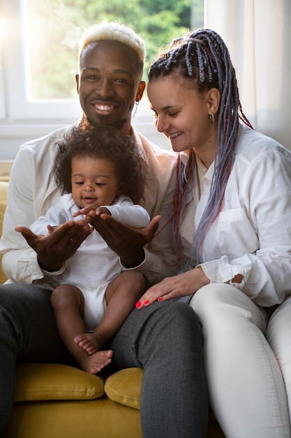 Foto lindo bebê preto em casa com os pais