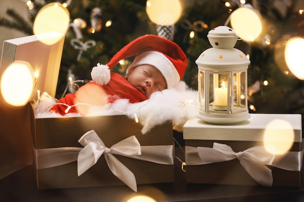 Foto lindo bebê recém-nascido com chapéu de papai noel está dormindo na caixa de presente de natal. feliz natal e feliz ano novo.