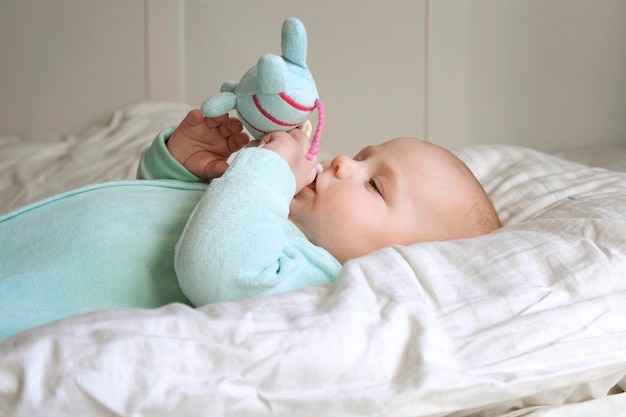 Lindo bebê recém-nascido deitado de costas e brincando com brinquedos coloridos Uma criança de três meses pega um retrato de brinquedo de uma criança recém-nascida brincalhona Conceito de infância Vida nova Cuidados com o bebê Vista superior