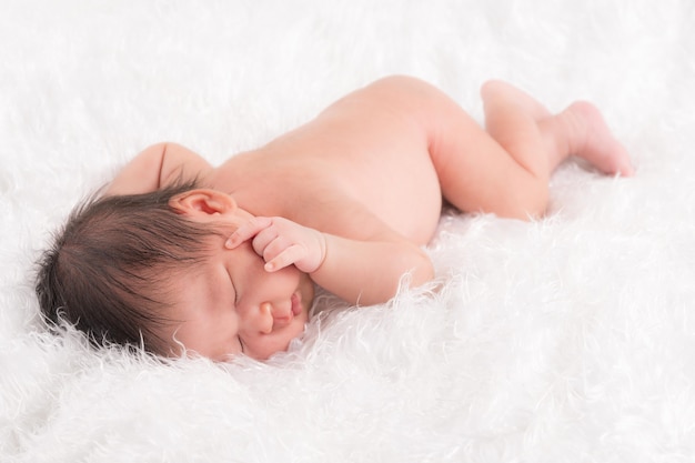 Lindo bebé recién nacido durmiendo boca abajo sobre un paño suave y esponjoso blanco