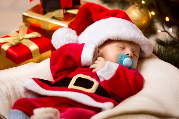 Lindo bebé recién nacido durmiendo en traje de Santa Claus blanco y rojo