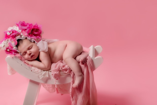 Lindo bebé recién nacido está durmiendo con flores sobre un fondo rosa