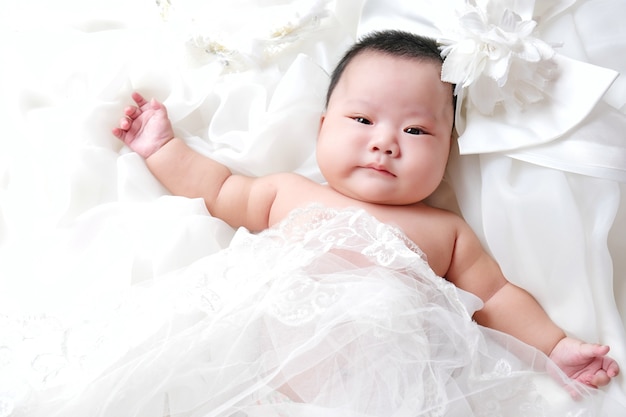 Lindo bebé recién nacido en el fondo blanco vestido de novia