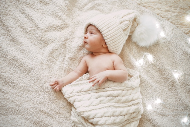 Lindo bebé recién nacido en un gorro de punto blanco sonriendo en un sueño