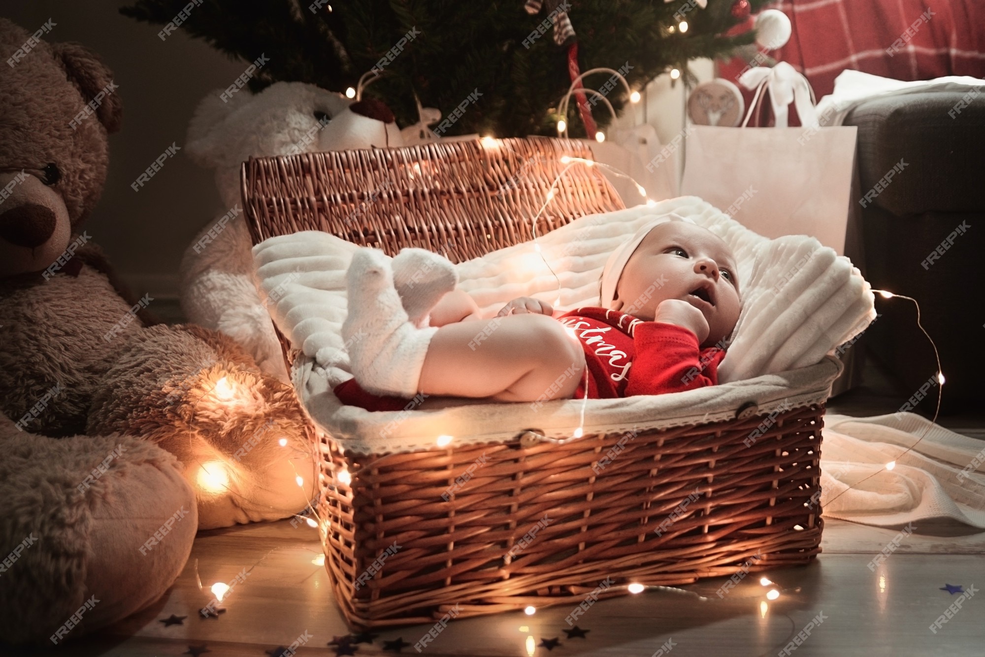 Un lindo bebé recién nacido en ropa de navidad durmiendo en una canasta en el suelo contra una decoración vispera de año | Foto Premium