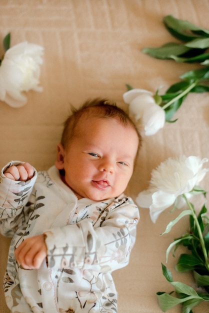 Lindo bebé en ropa estampada de flores en peonías