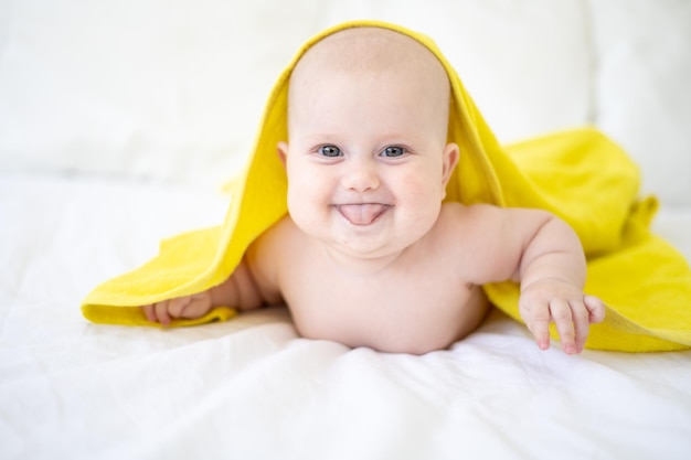 Un lindo bebé sano y feliz está acostado boca abajo después de bañarse en una toalla y sonriendo