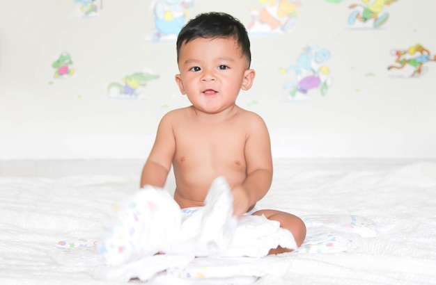 Lindo bebé sentado en una alfombra mullida en casa. El bebé tiene 8 meses. - Personas, concepto de salud. Enfoque suave, enfoque selectivo.