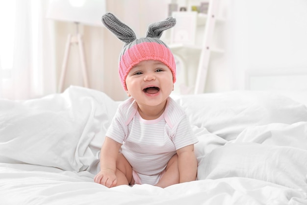 Foto lindo bebé sentado en la cama en casa