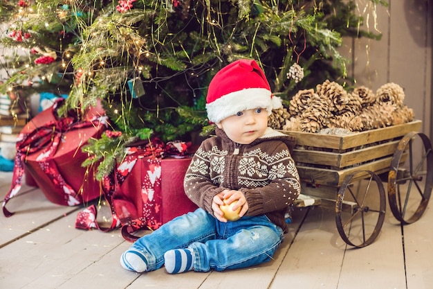 Lindo bebé sentado cerca del árbol de Navidad