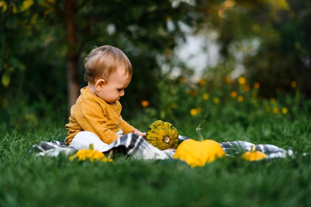 lindo bebé sentado en la hierba con la cosecha de verduras