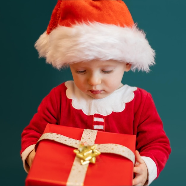 Lindo bebé con sombrero rojo de Santa con regalo de Navidad en la mano Concepto de Navidad