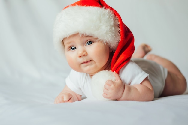 Lindo bebé con sombrero de santa en blanco.