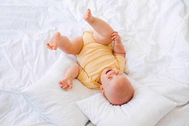 Lindo bebé sonriendo se encuentra en la cama de la casa. ropa de cama para niños