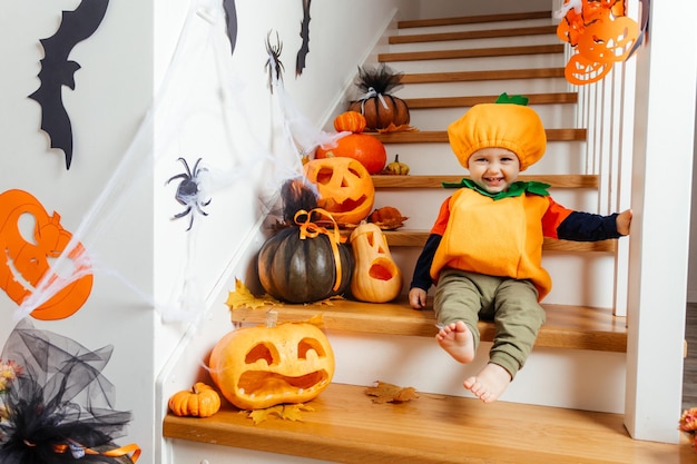 Lindo bebé sonriente vestido como calabaza mirando a la cámara