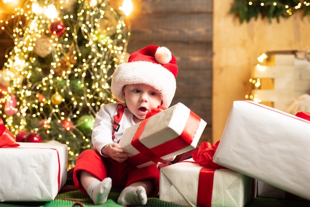 Lindo bebé sorprendido cerca del árbol de Navidad.