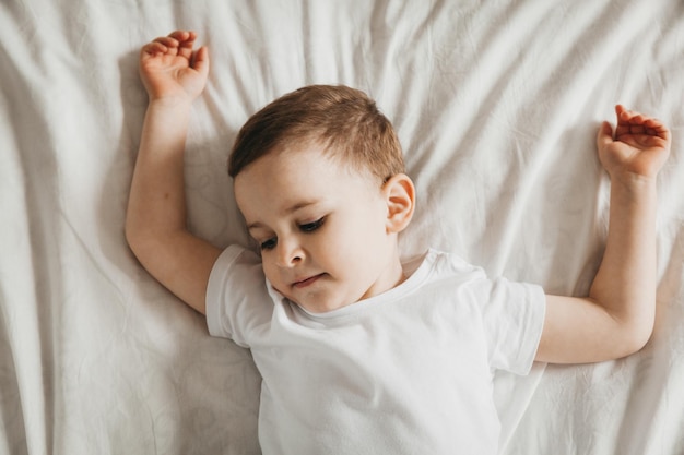 Lindo bebé yace en la cama retrato de vista superior de un niño en la cama