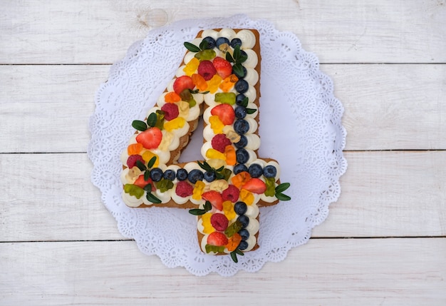 Lindo bolo de aniversário em forma de quatro figuras em um branco
