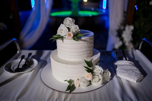 Lindo bolo de casamento à noite perto do arco