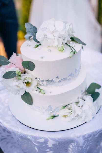 Lindo bolo de casamento fechado de um bolo decorado com flores brancas e folhas verdes