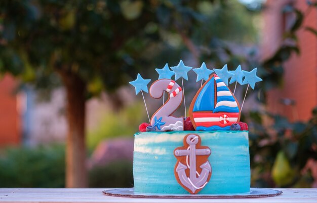 Lindo bolo para o aniversário de uma criança com o número dois e uma âncora de navio no jardim de verão
