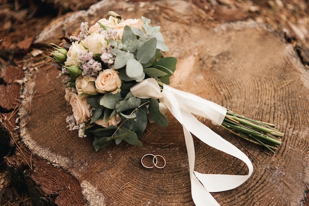 Lindo buquê de casamento com protea e alianças de rosas em um fundo de floresta