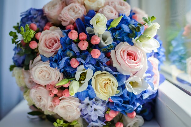 Lindo buquê de flores azuis e rosa, rosas perto da janela