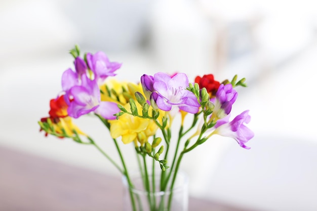 Lindo buquê de flores coloridas frésias na mesa de madeira na sala de estar