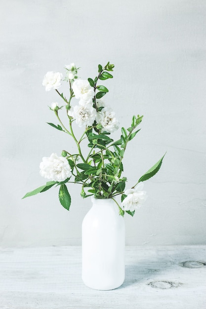 Lindo buquê de flores de rosas brancas em um vaso branco na mesa cinza