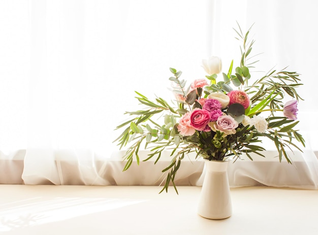 Lindo buquê de flores delicadas com rosas eustomas e folhas de eucalipto em um vaso no parapeito da janela dia das mulheres dia das mães e celebração do dia dos namorados