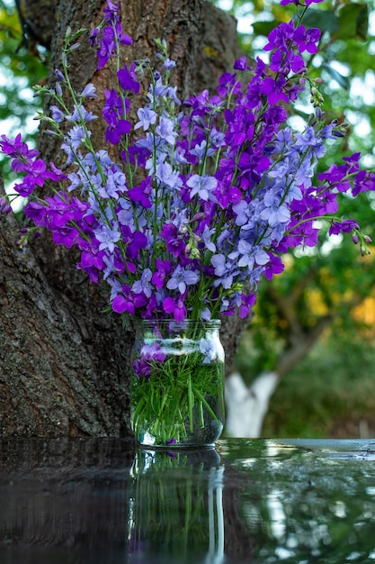 Lindo buquê de flores para casa delphinium azul e roxo em uma jarra de água