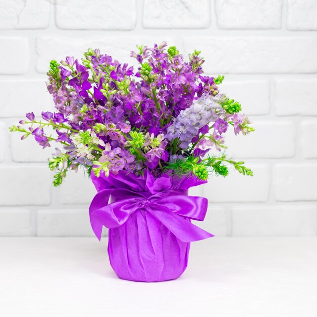 Lindo buquê de flores roxas lilás em um vaso em um fundo branco Cartão de dia das mães Lugar para uma inscrição